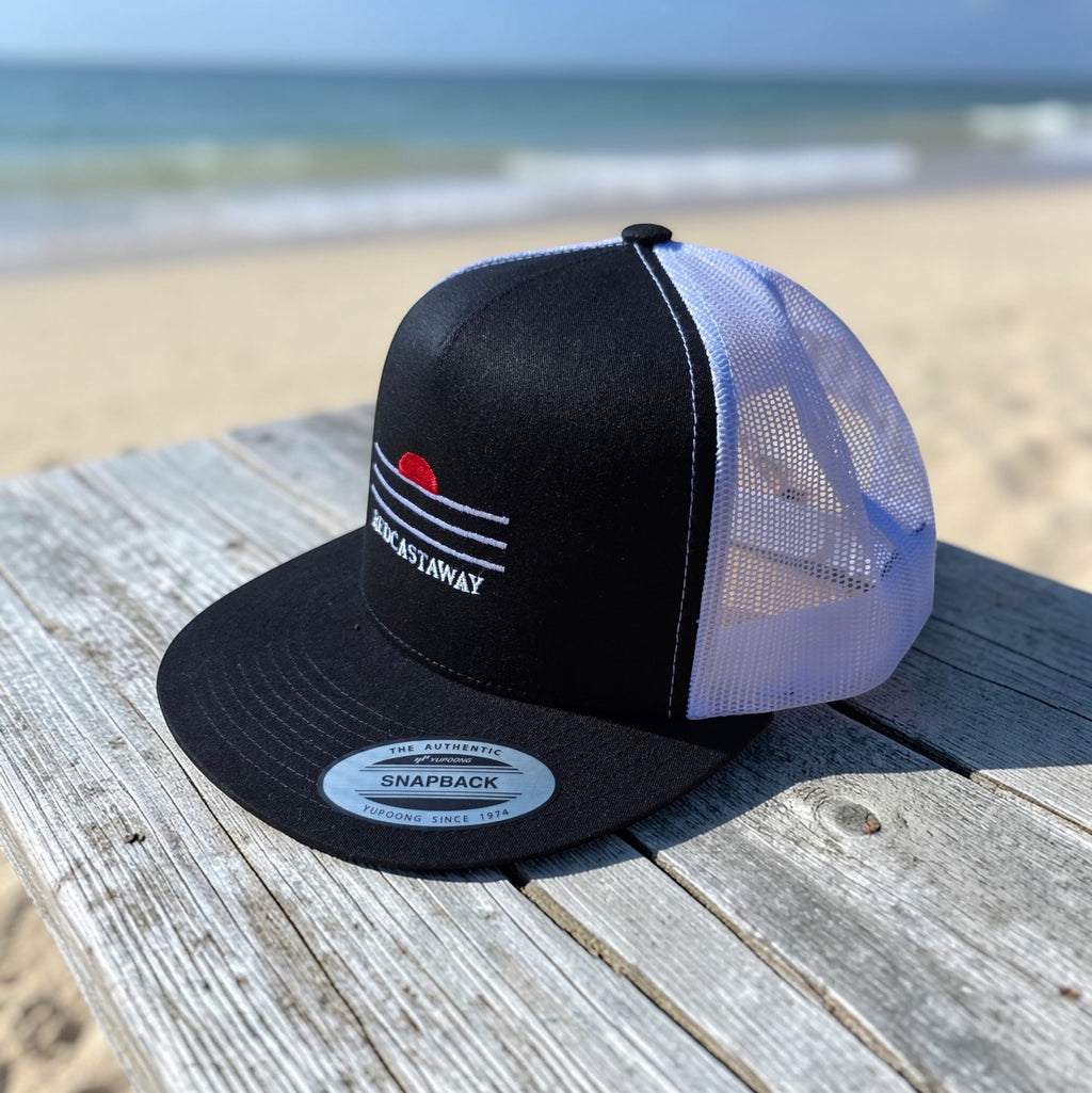 Redcastaway black trucker cap with white mesh back and embroidered coastal logo. Flat bill, snapback closure.
